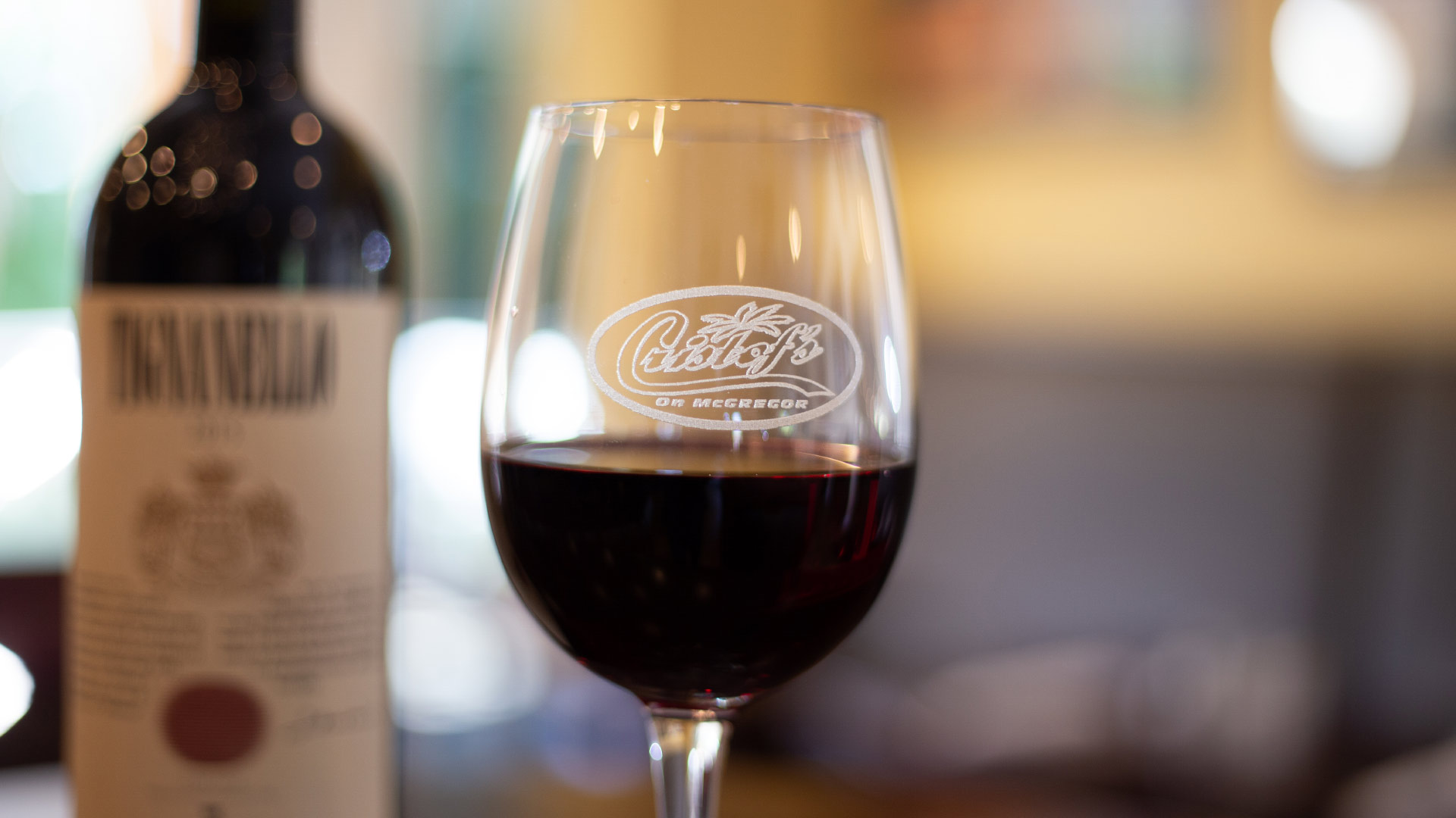 A glass of red wine bearing the Cristof’s logo